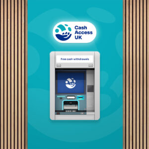 Silver cash machine in the wall that is surrounded by teal coloured Cash Access UK branded graphics and anatural wood background. Cash Access UK logo above cash machine.