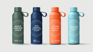 Four water bottles in different colours with text in different languages promoting global cooperation and protecting life on earth. The bottles are green, blue, orange, and light blue, and have labels in Chinese, English, Arabic, and French. The labels also have the UN logo on them. The bottles are part of the UN Environment Programme’s campaign for the World Ozone Day 2022. Design concept by 400.