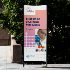 a tall billboard outside on a sunny street, advertising an event for the WHO Global Lab Recognition programme